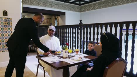 Muslim-family-serves-food-in-hotel