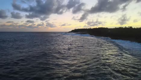 Eine-Drohnenaufnahme-Mit-Niedrigem-Aufstieg-Fängt-Die-Wellen-Ein,-Die-An-Der-Küste-Vor-Der-Kulisse-Eines-Sonnenuntergangs-Auf-Big-Island,-Hawaii,-Brechen