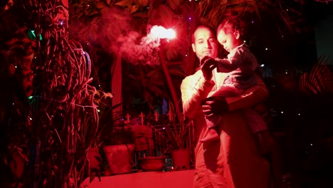father-and-son-celebrating-diwali-by-burning-sparkler-at-night-from-different-angle