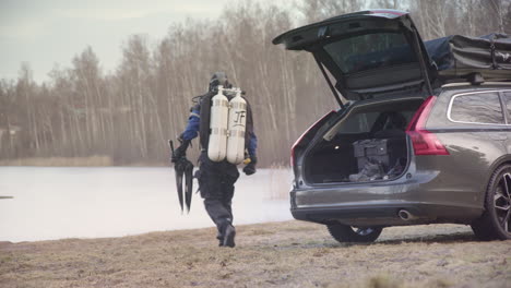 Geared-up-ice-diver-walks-from-open-car-boot-toward-lake-for-penetration-dive