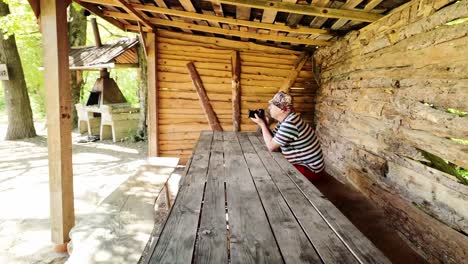 älterer-Fotograf-Saß-An-Einem-Picknicktisch-Im-Sommerwald-Und-Machte-Fotos