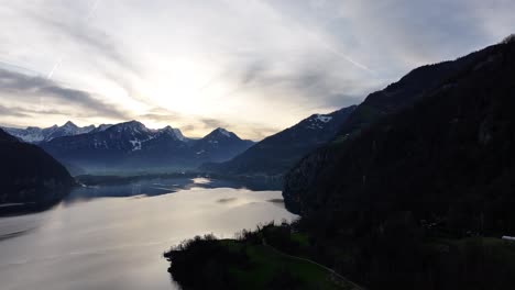 Sunrise-over-Walensee,-Walenstadt,-Weesen,-Quinten,-and-the-Churfirsten-mountains,-Switzerland,-with-captivating-drone-footage-of-misty-clouds-and-fog-enveloping-the-serene-mountains-and-river