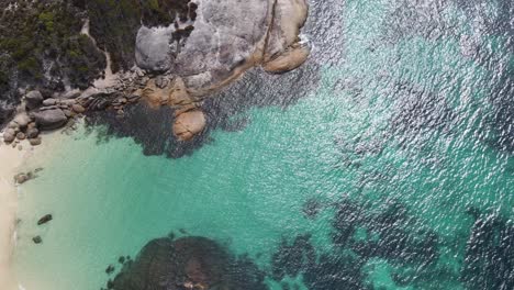 Drone-aerial-over-coastal-rock-with-bright-blue-water-in-Australia