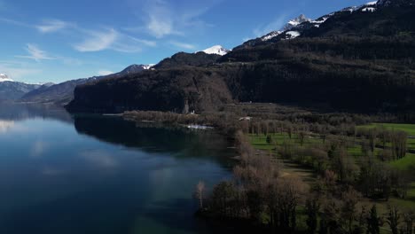Drone-clip-showing-calm-lake-with-snow-topped-mountains-on-a-fresh-sunny-day-in-the-Swiss-Alps
