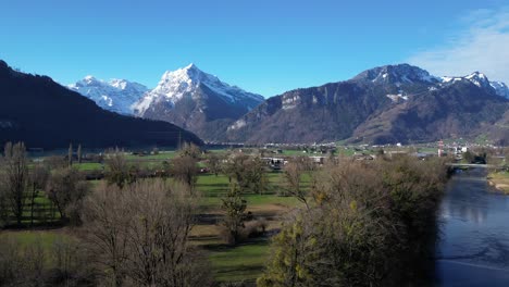 Drohnenclip,-Der-Malerische-Schneebedeckte-Berge-Und-Grasbedeckte-Niederungen-In-Den-Alpen-Zeigt