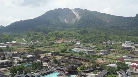 Panaroma-of-Mount-Sibayak,-aerial-drone-fly-over-the-pariban-hot-springs-residential-valley-at-Berastagi,-North-Sumatera,-Indonesia