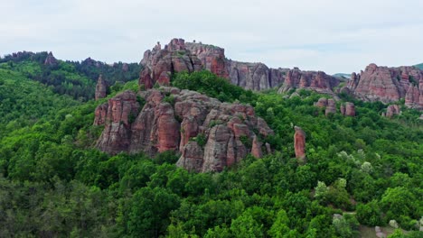 Drone-flies-over-green-forests-to-Belogradchik-sandstone-rock-formations-landscape