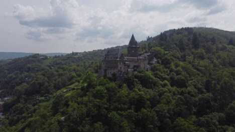 Castillo-Medieval-De-Stahleck-En-Lo-Alto-De-Una-Exuberante-Colina-Verde-En-Bacharach,-Alemania,-Vista-De-Drones