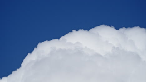 Slow-bloom-of-puffy-cotton-like-white-cloud-in-blue-sky,-time-lapse
