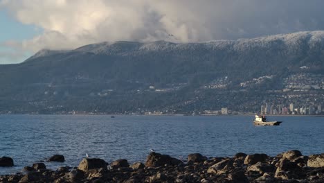 Tug-Boat-Floating-In-The-Calm-Sea-With-Mountains-In-The-Background