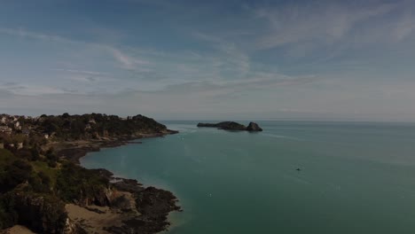 Aerial-4K-Drone-footage-of-the-coast-of-Cancele,-Brittany,-France-along-the-beautiful-coast-line-and-rotating-around-to-a-rocky-beach-that-has-a-natural-swimming-pool