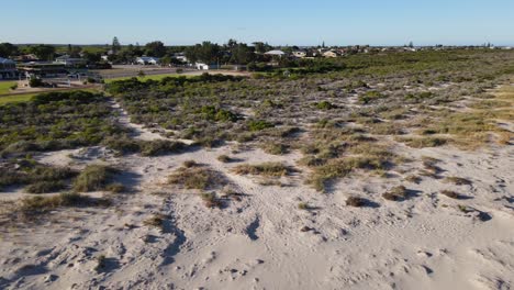 Drone-aerial-over-coastal-town-panning-down-to-reveal-white-sand-beach