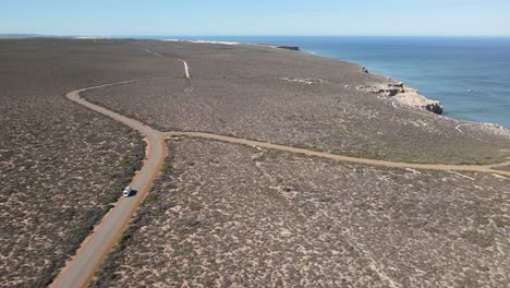 Drone-aerial-over-a-campervan-on-a-long-road-by-a-beautiful-ocean