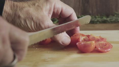 senior-housewife-cut-cherry-tomato-in-a-wooden-board-kitchen-table-with-sharp-knife