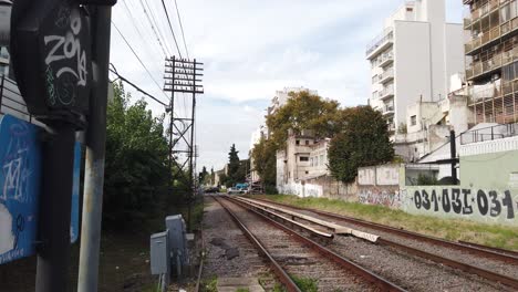 Argentinischer-Eisenbahnzug-Fährt-Ohne-Menschen,-Stadtautos,-Querverkehr-Im-Hintergrund