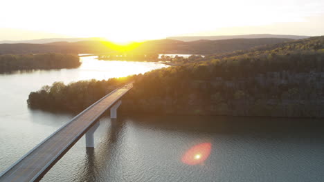 Aerial-flyover-of-a-car-that-is-driving-across-a-bridge-on-Nickajack-Lake-during-the-sunset-golden-hour-in-Tennessee