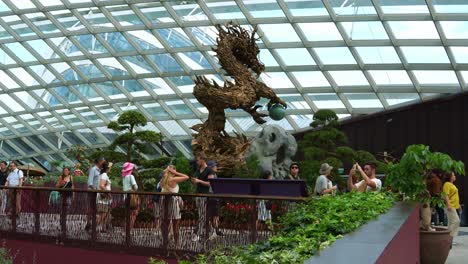 Vista-Panorámica-Que-Captura-El-Interior-Del-Invernadero-De-Cristal-Con-Cúpula-De-Flores,-Que-Presenta-Una-Escultura-De-Dragón-De-Madera-Durante-La-Temporada-Festiva,-Para-Celebrar-El-Año-Nuevo-Lunar-En-Los-Jardines-Junto-A-La-Bahía