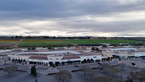 Drone-Flight-Carlsbad-Premium-Outlets-Covering-Northwest-Corner-of-Mall-Moving-towards-North-End-Flower-Fields-Background-Partial-Bloom-Colorful-stripes-and-Green