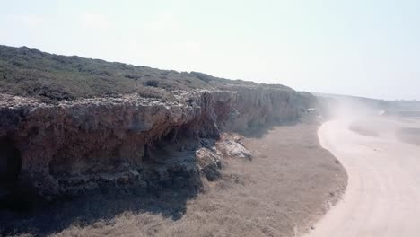 Off-road-along-natural-layered-rock-formation-resembling-a-sheer-cliff