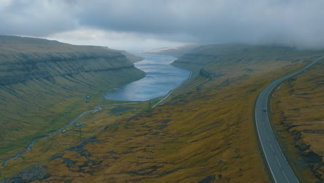 Malerischer-Roadtrip:-Luftaufnahmen-Des-Autos,-Gefolgt-Von-Einer-Drohne,-Die-Die-Atemberaubende-Landschaft-Der-Färöer-Inseln-Einfängt