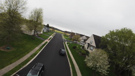 Black-car-on-road-in-suburbia-of-USA-during-grey-cloudy-day