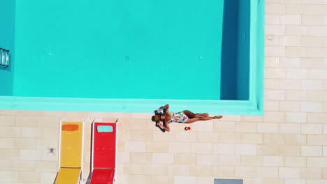 Woman-in-swimsuit-lying-and-sunbathing-at-pool-edge