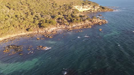 Drone-aerial-at-a-national-park-panning-down-to-reveal-a-bright-blue-beautiful-ocean