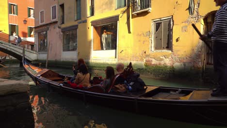 Gondola-with-venetian-oarsmen-gondolier-sails-through-water-canal-in-Venice