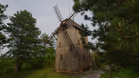 Old-Windmill-wooden-storage-house,-countryside-forest-cloudy-skyline-pine-trees