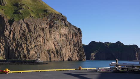 Port-of-Vestmannaeyjar,-Heimaey-Island,-Iceland-on-Sunny-Day,-Steep-Cliffs-Above-Sea-and-Dock
