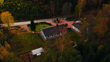 Aerial-view-circling-a-private-family-home-in-middle-of-fall-colored-woods