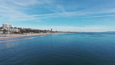 Slow-cinematic-drone-shot-close-to-the-water-over-Santa-Monica-Beach