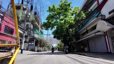 Ground-level-view-of-Manila's-bustling-traffic-filmed-from-inside-a-tuk-tuk,-capturing-the-city's-lively-streets