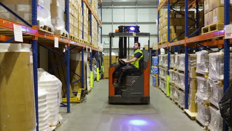 worker-driving-electric-forklift-inside-a-warehouse-,-Logistic-distribution-industrial-interior