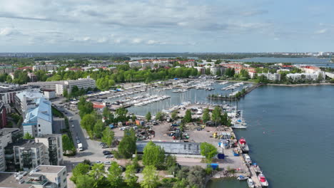 Aerial-view-rising-toward-the-Lauttasaari-marina,-sunny-spring-day-in-Helsinki
