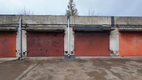 Vista-En-Movimiento-De-La-Cámara-Del-Antiguo-Garaje-Vintage-Oxidado-De-Hormigón-Construido-Con-Puertas-Metálicas-Coloridas-Durante-El-Día