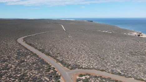 Panorámica-Aérea-De-Drones-Que-Muestra-Una-Caravana-En-Un-Largo-Camino-Junto-A-Un-Hermoso-Océano.