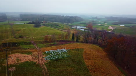 Vista-Aérea-Rodeando-Pilones-En-El-Suelo,-Construcción-De-Cables-Eléctricos,-Día-De-Otoño