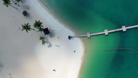 Aerial-drone-view-of-people-walking-around-near-zip-line-with-palm-trees-on-sandy-Siloso-ocean-beach-Sentosa-Island-Singapore-Asia-tourism-travel