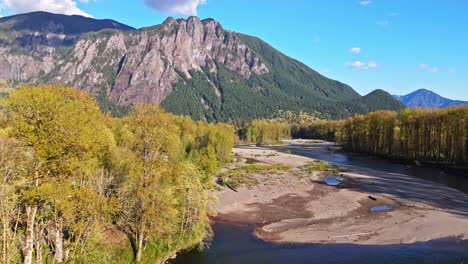 Scenic-drone-view-flying-over-Snoqualmie-Middle-Fork-River-with-Mount-Si-in-the-background-during-a-blue-sky-day-in-North-Bend,-Washington-State