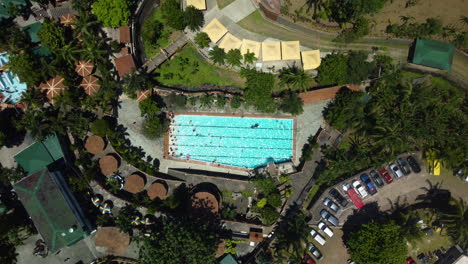 Fixed-overhead-drone-shot-of-people-in-swimming-pool,-on-a-sunny-summer-day