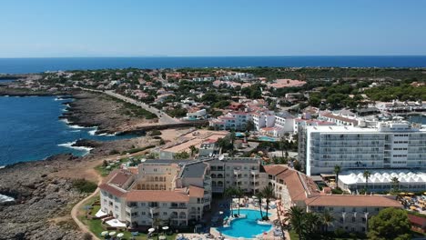 Toma-Aérea-De-Un-Hotel-De-Vacaciones-De-Verano-Con-Piscina-En-Menorca,-España.