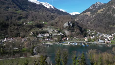 Drohnenclip-Eines-Traditionellen-Schweizer-Dorfes-Am-Ufer-Des-Walensees,-Umgeben-Von-Schneebedeckten-Bergen