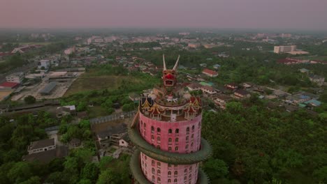 Rotación-Aérea-Que-Muestra-El-&quot;templo-Del-Dragón&quot;-Wat-Sam-Phran,-Un-Impresionante-Templo-Cilíndrico-De-Color-Rosa-De-17-Pisos-Adornado-Con-Un-Enorme-Dragón-Verde-Que-Rodea-Su-Estructura,-Situado-En-Bangkok.