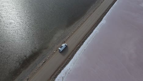 Drone-aerial-spin-around-campervan-on-road-over-pink-lake-MacDonnell-in-South-Australia