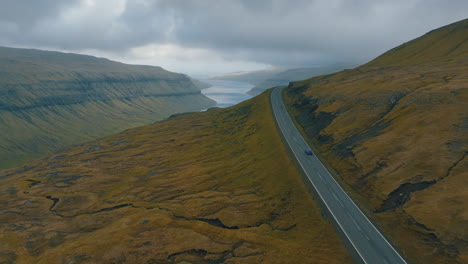 Panoramafahrt:-Luftbildaufnahme-Eines-Autos,-Das-Mit-Einer-Drohne-Durch-Die-Spektakuläre-Landschaft-Der-Färöer-Inseln-Fährt