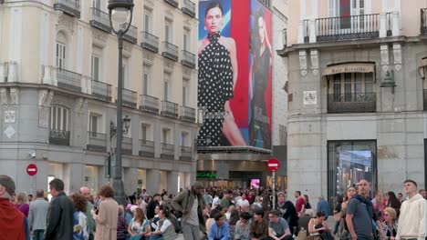 Menschen-Versammeln-Sich-An-Der-Puerta-Del-Sol,-Eingerahmt-Von-Der-Erkennbaren-Mode-Einzelhandels-Reklametafel-Im-Hintergrund,-In-Madrid,-Spanien