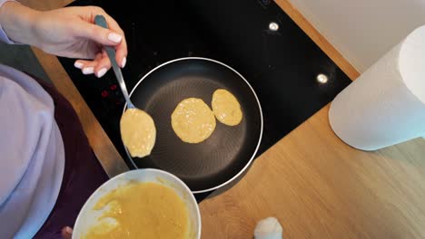 Top-down-shot-of-a-woman-preparing-pancakes-in-the-kitchen-at-home-in-the-morning-for-breakfast