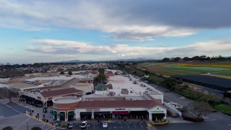 Drone-Flight-Carlsbad-Premium-Outlets-Covering-South-End-of-Mall-Moving-towards-Southwest-Corner-Flower-Fields-side-Background-Partial-Bloom-Colorful-stripes-and-Green