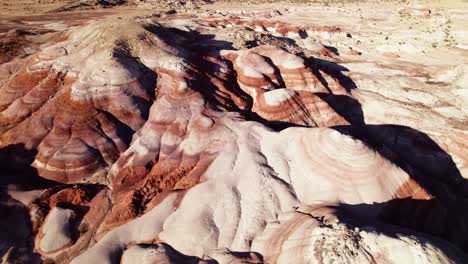Aerial-4k-drone-reverse-flyover-view-of-Bentonite-Hills,-Utah,-at-golden-hour-with-colorful-mars-like-landscape